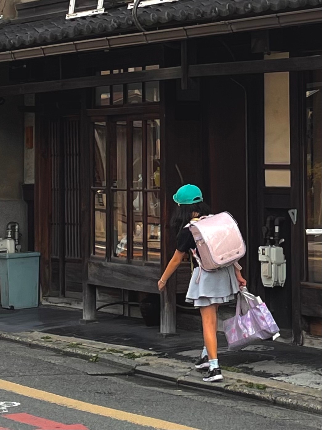 Девочка идёт из школы. Рюкзак традиционный, они плюс минус одинаковой формы. Размером с саму девочку :)