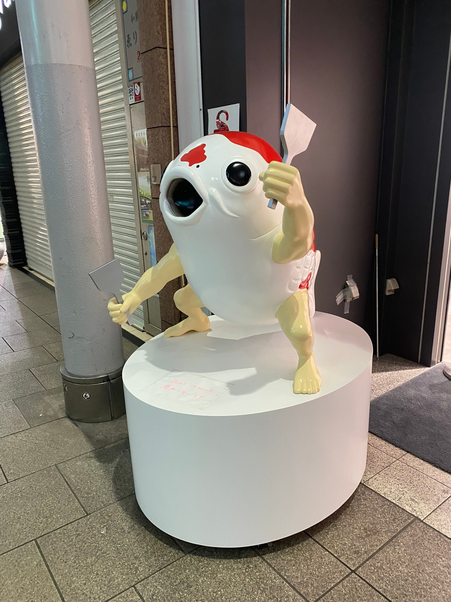 Окономияки - блюдо Осаки. Рыба держит в руках лопаточки для поедания